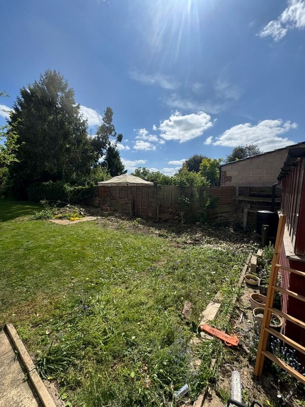 Cut vegetation gathered on a lawn next to raised timber decking
