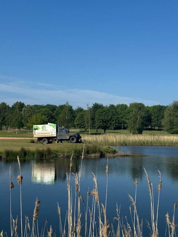 Tipper truck parked on the far bank of a lake fringed with reeds