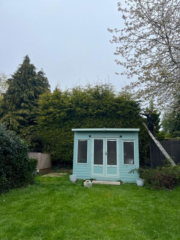 Summerhouse on a mown lawn framed by trees in spring blossom