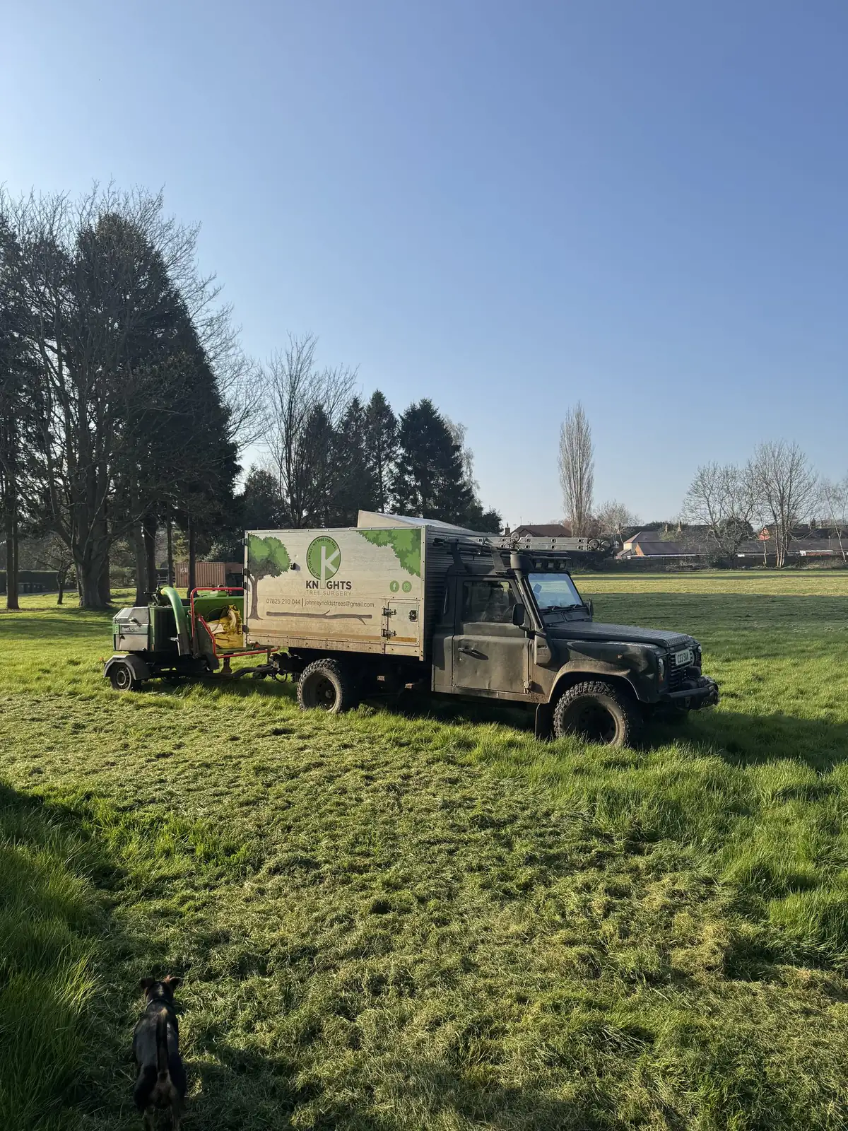 Knights Tree Surgery branded Land Rover and woodchipper parked on a field