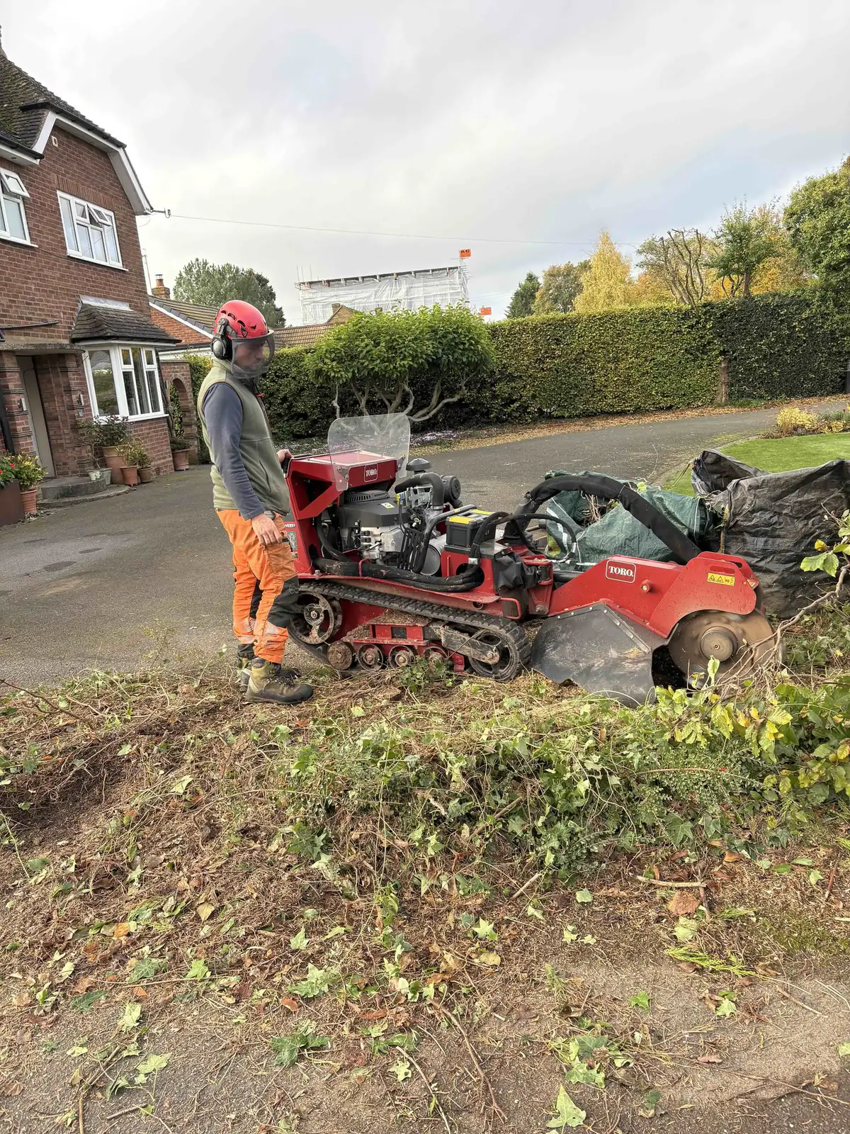 Operator using a tracked stump grinder on a driveway